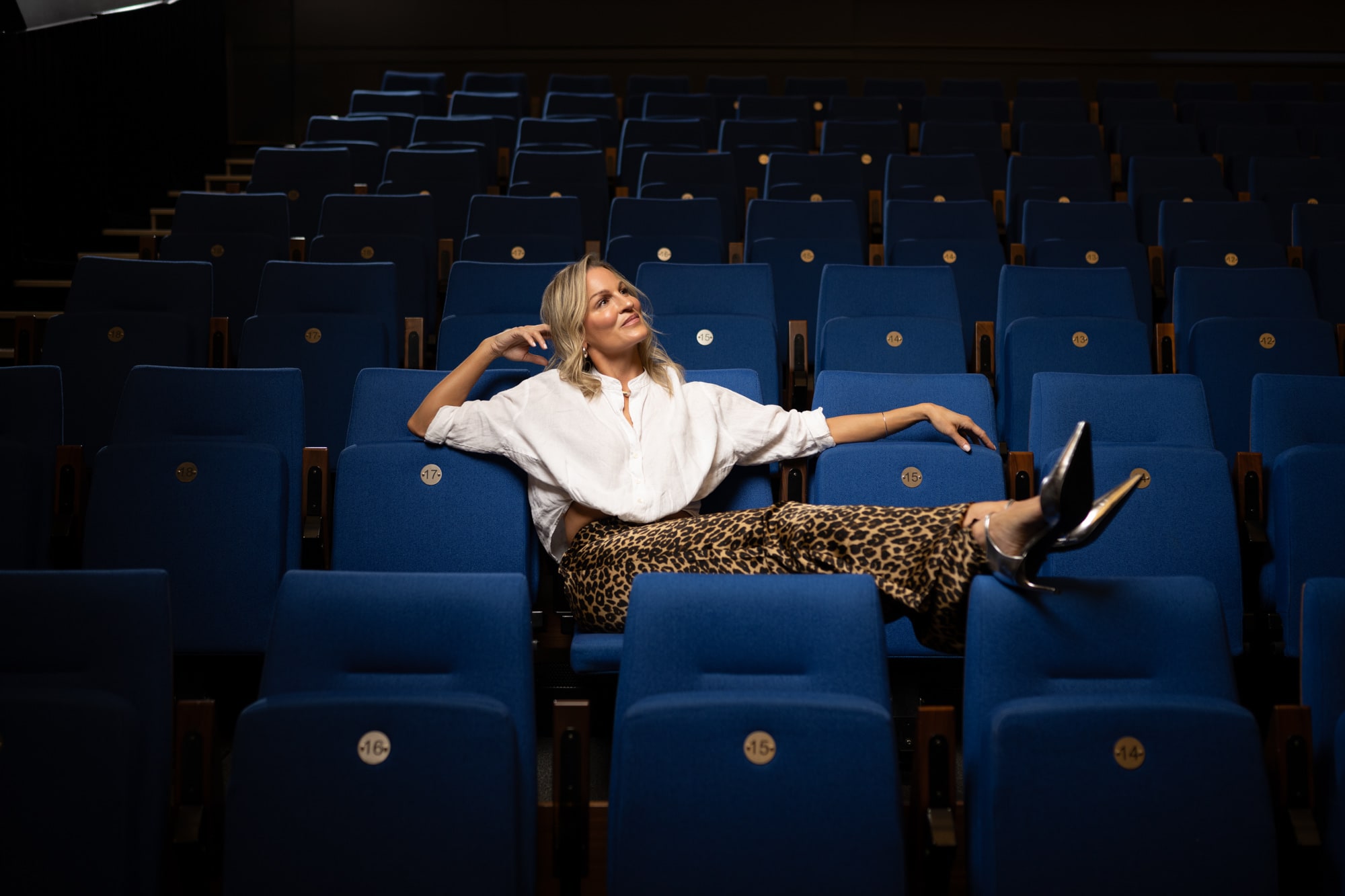 Dr. Marie Claire Bourque seated in an empty blue theatre, looking up